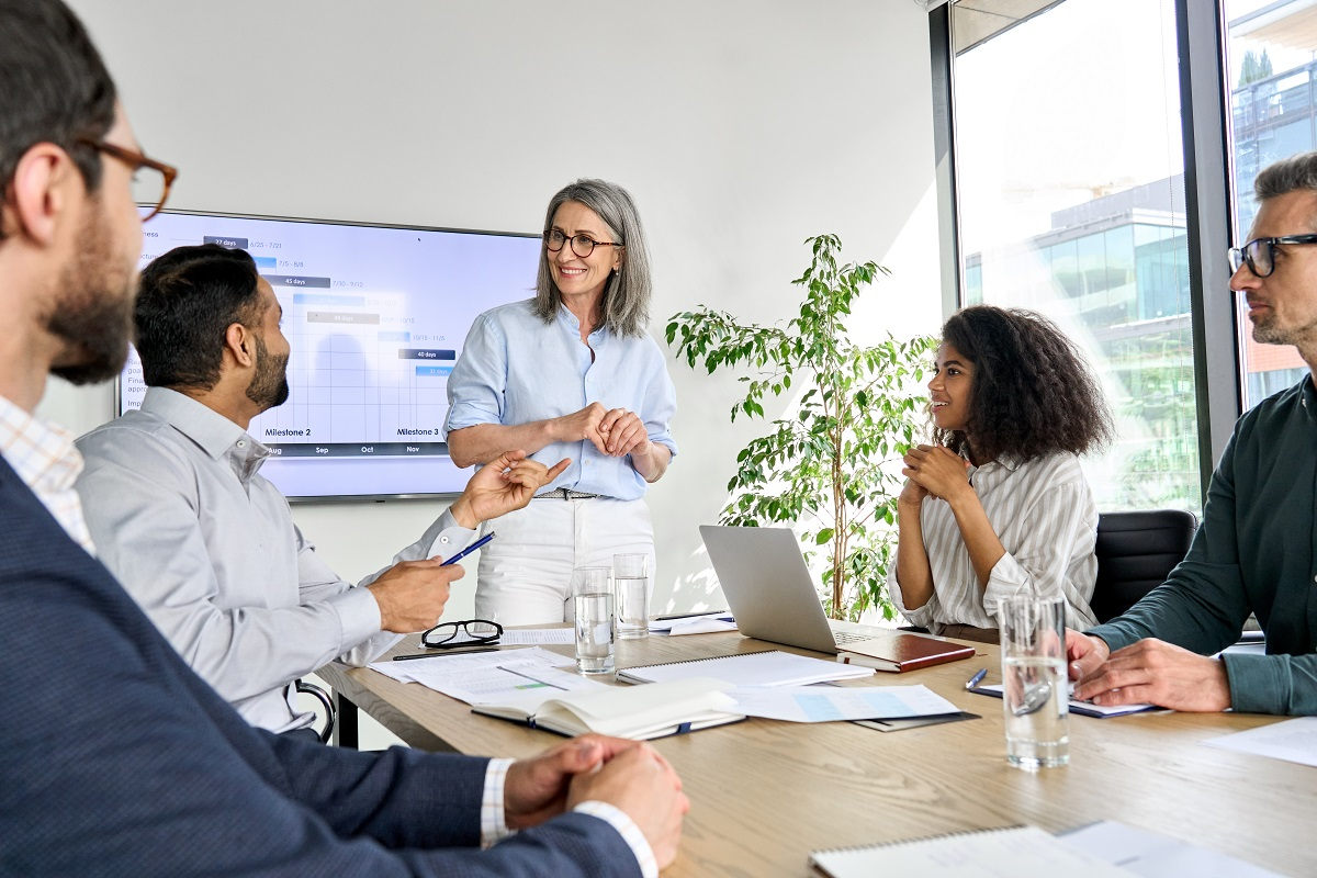 A group of five diverse professionals in a modern conference room engaged in a corporate development meeting.