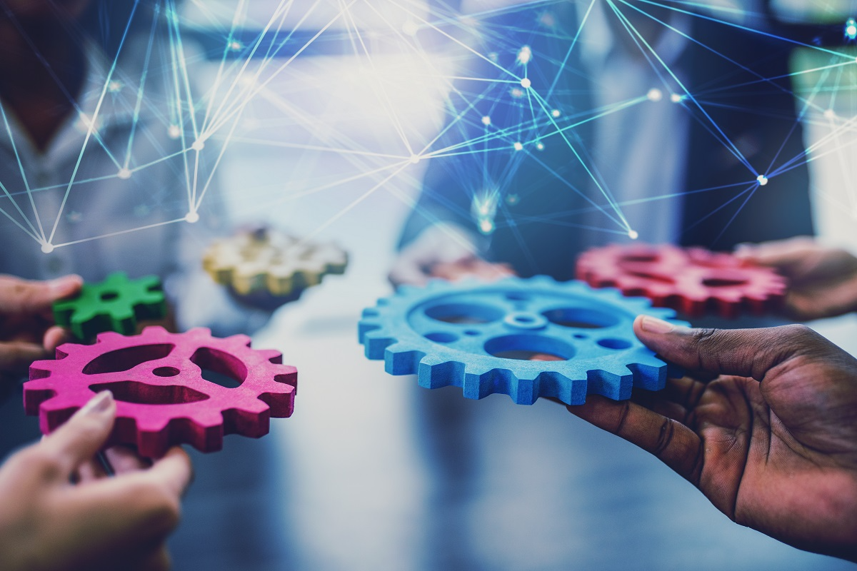 Close-up of hands holding colorful interlocking gears, symbolizing AI used in corporate roll-ups
