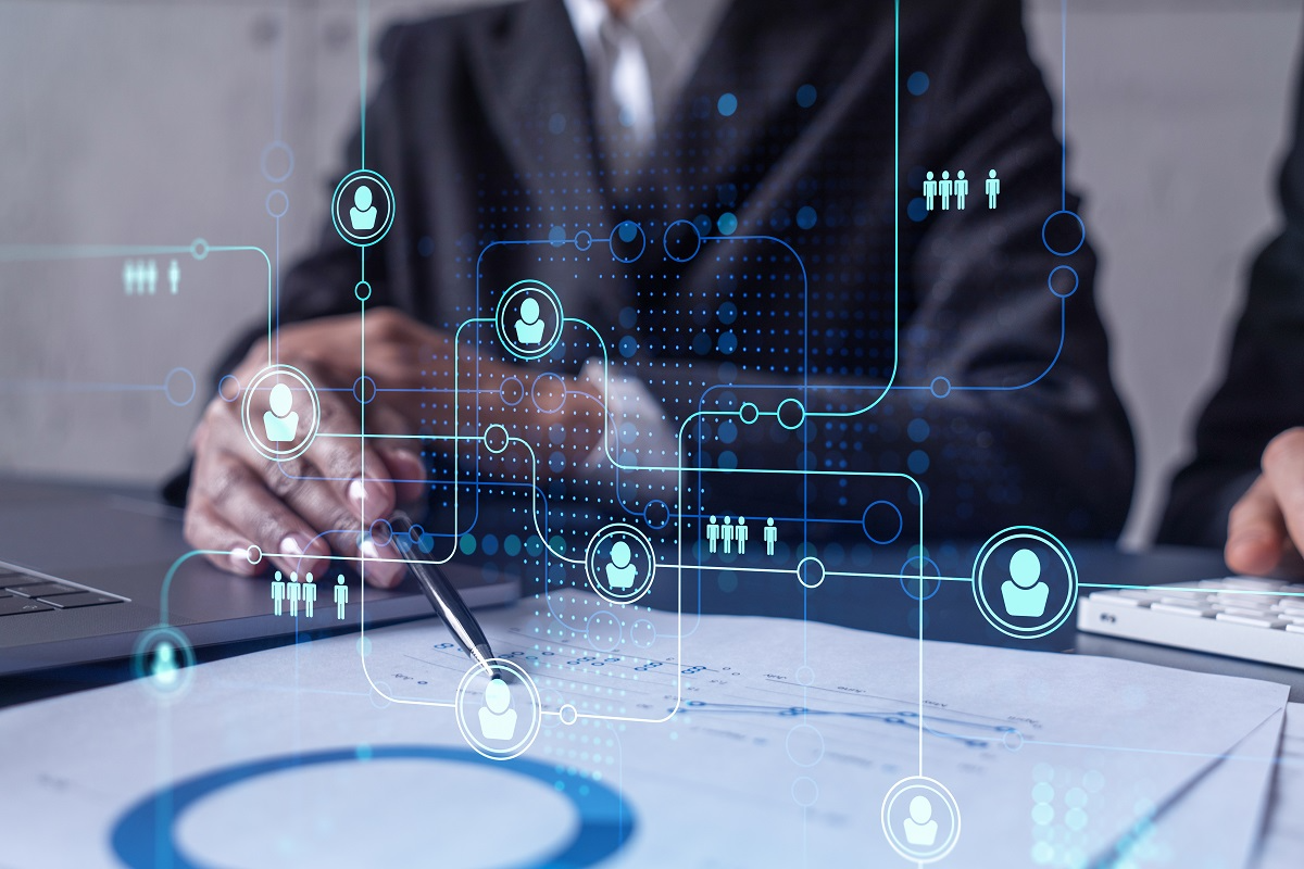 Close-up of executives using a laptop and documents with digital icons representing people and connections, symbolizing stakeholder and HR due diligence
