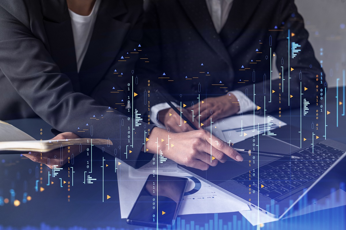 Business professionals reviewing M&A due diligence data on a laptop with overlaid digital financial graphs and analytics