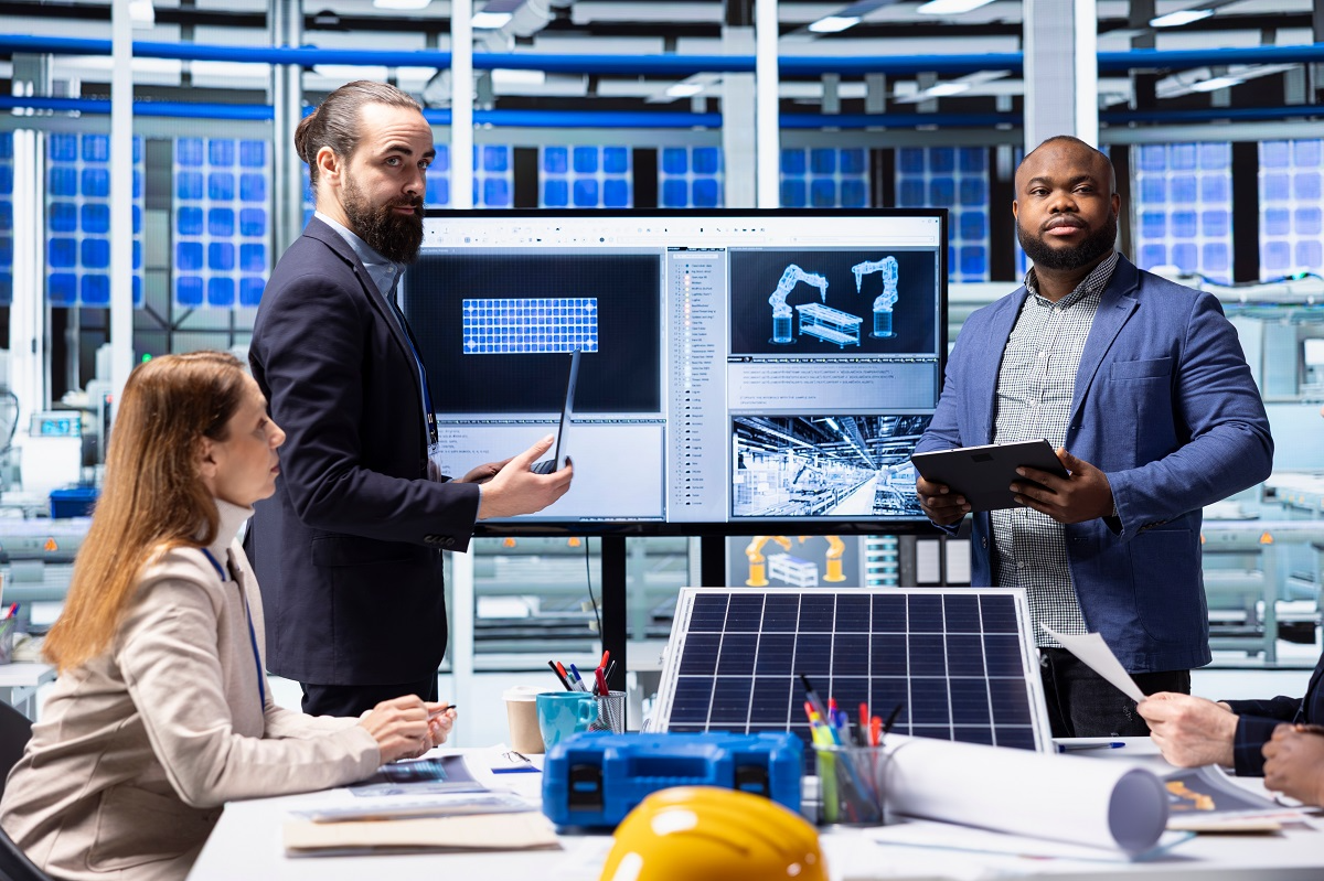 Management team conducting a site visit and operational review with CAD drawings and manufacturing equipment, highlighting operational due diligence