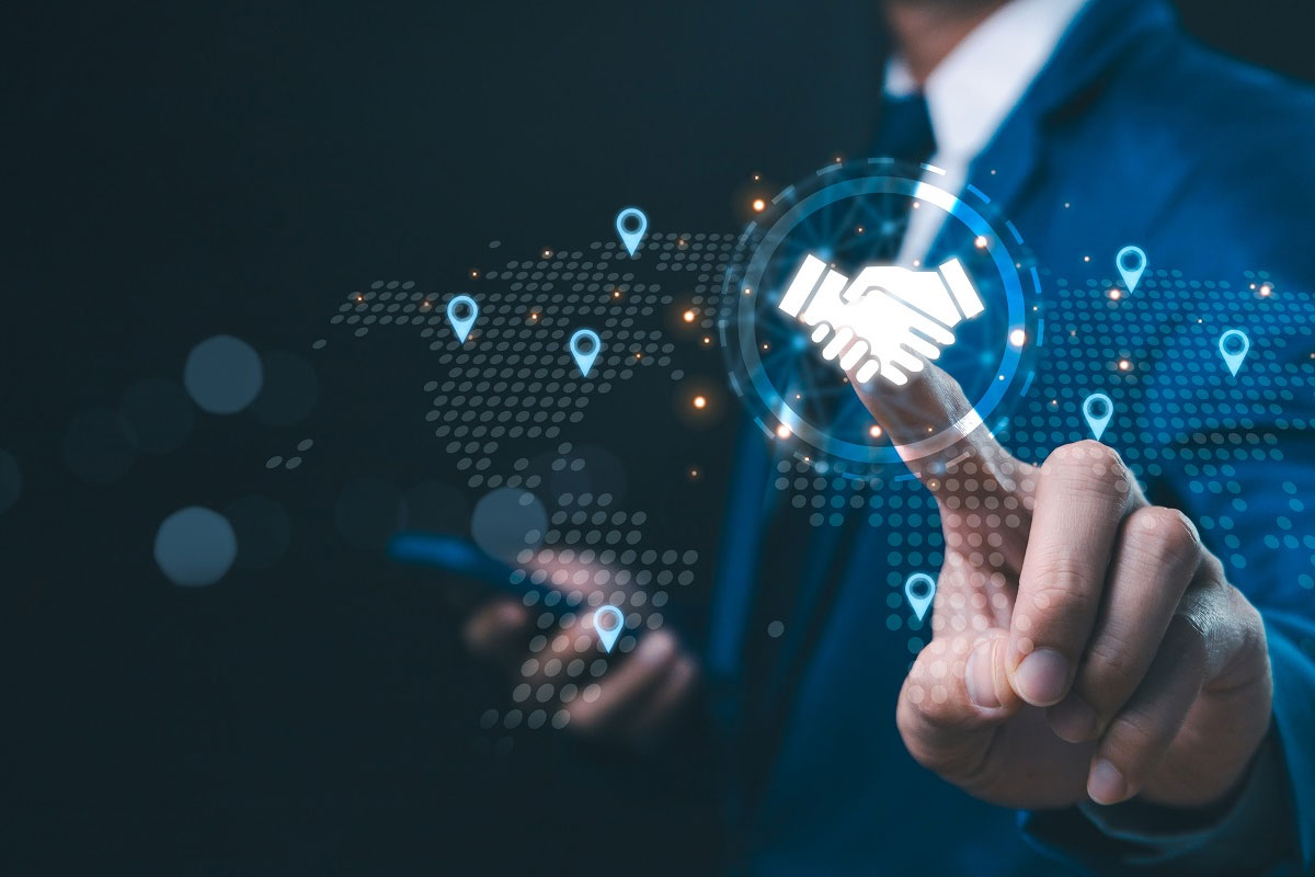 Businessperson in a suit activating a virtual handshake icon on a world map interface with location markers, symbolizing global M&A technology solutions and cross-border deal collaboration