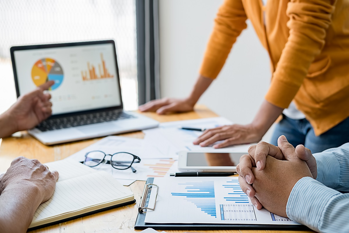 Financial advisors reviewing charts and market data during a buy-side M&A strategy meeting