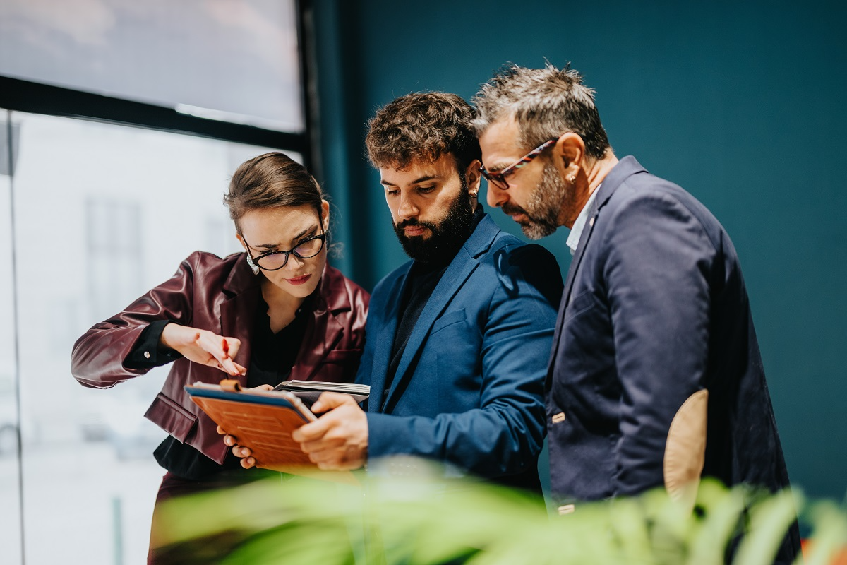 Business professionals reviewing acquisition opportunities and deal pipeline on a digital tablet.