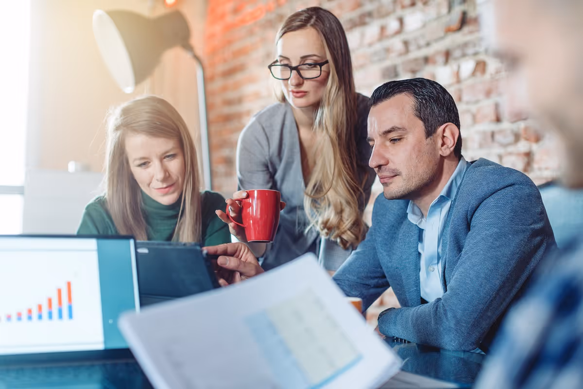Team of professionals reviewing market data and financial charts during a buy-side commercial due diligence meeting, assessing business performance and investment potential