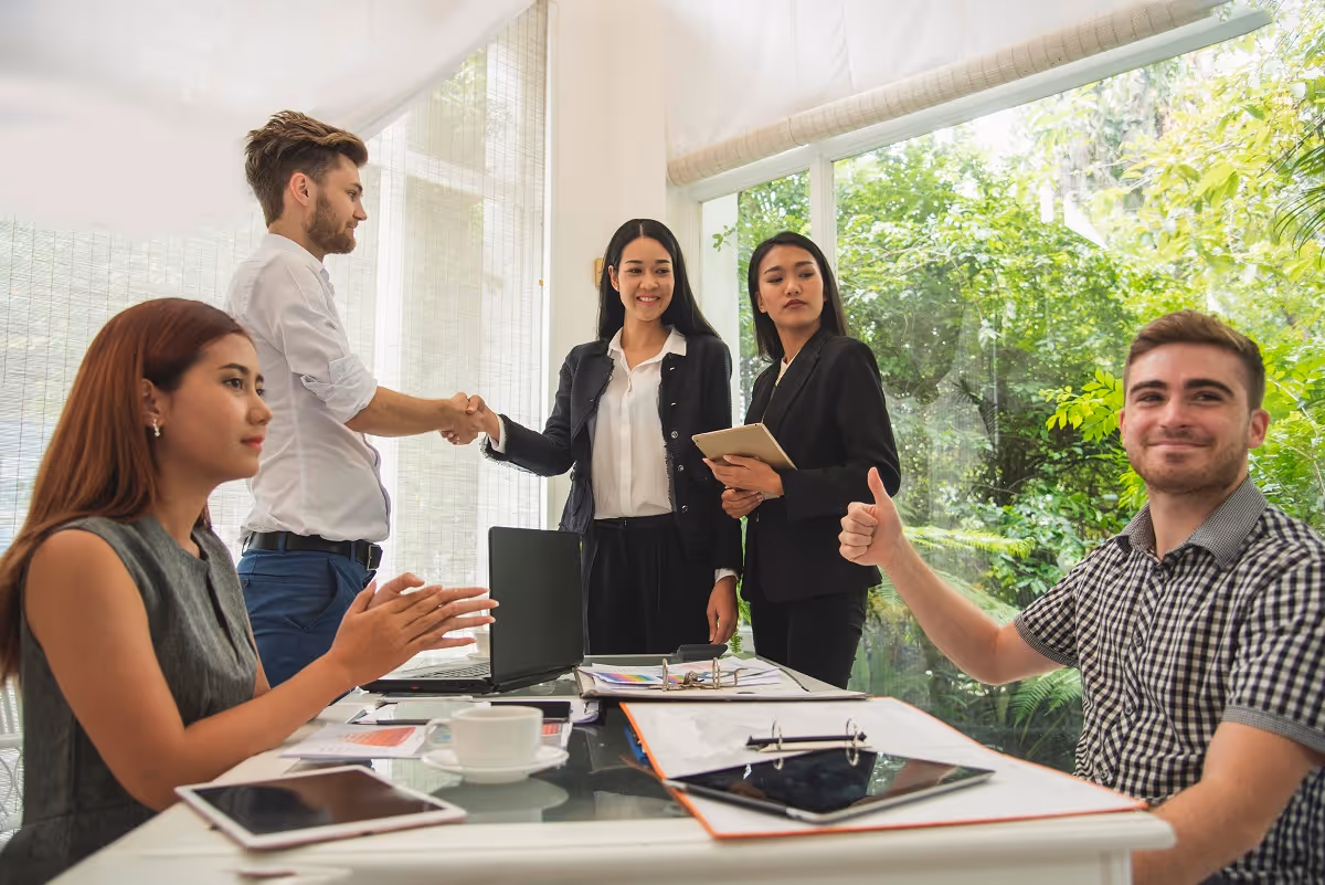Business professionals shaking hands and celebrating a successful deal during an M&A meeting