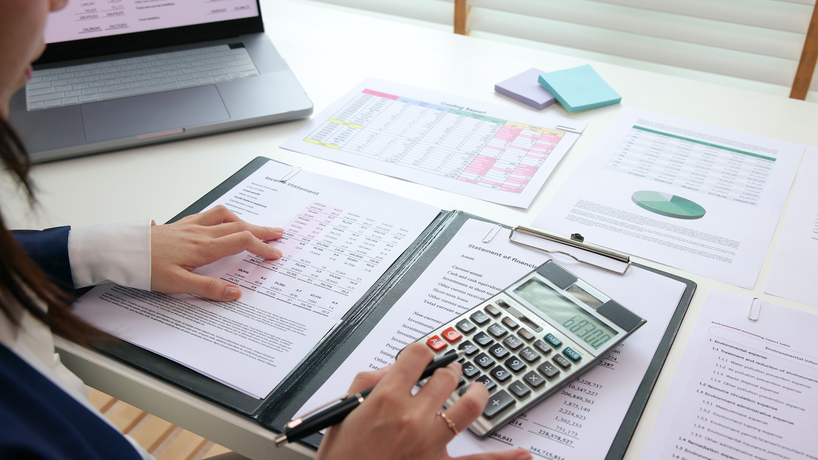 Finance professional analyzing financial statements and balance sheets with a calculator as part of buy-side financial due diligence