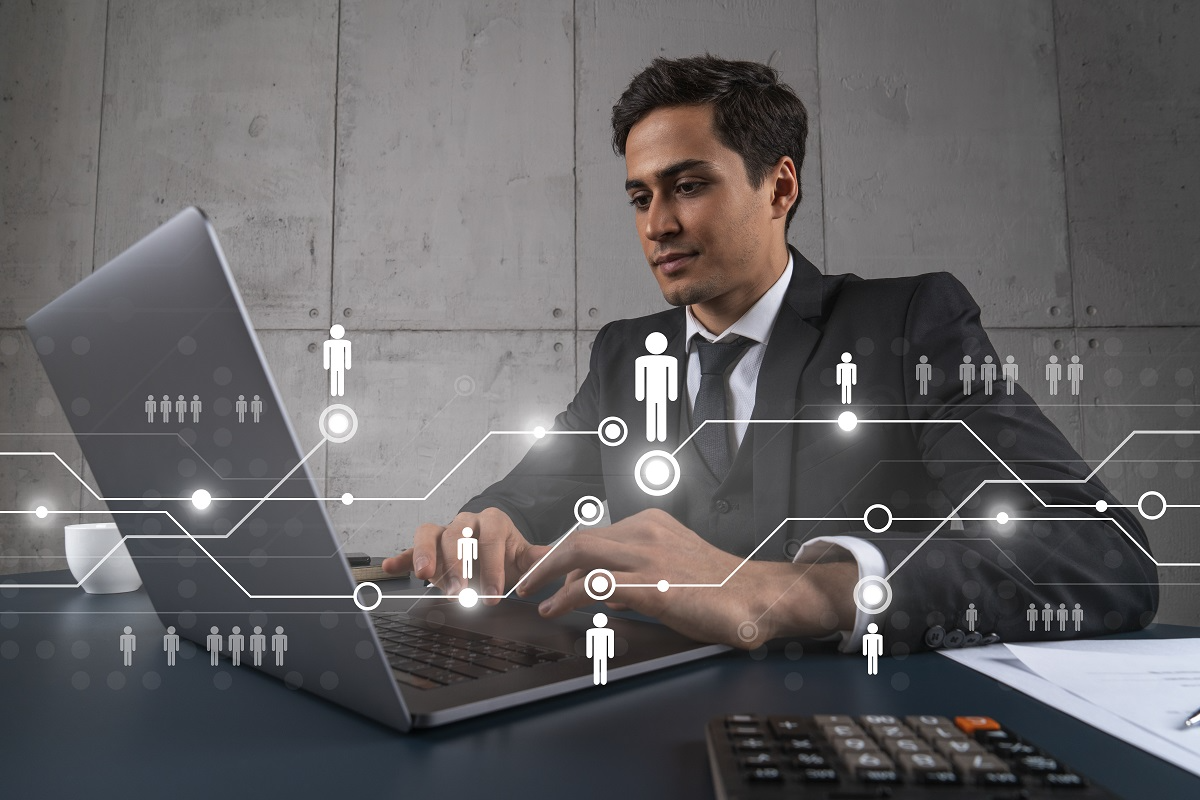 Business professional analyzing deal data on laptop with digital network overlay