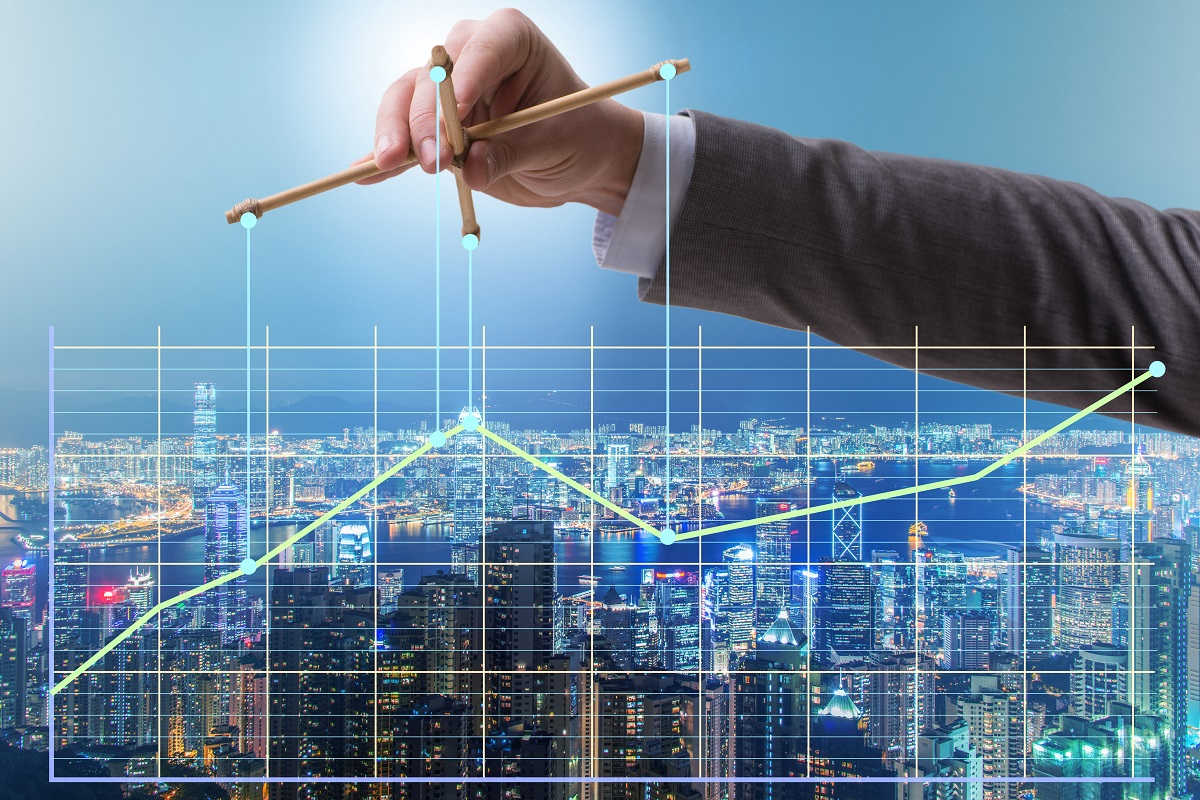 Business hand adjusting a rising financial chart over a city skyline, representing growth through mergers and acquisitions