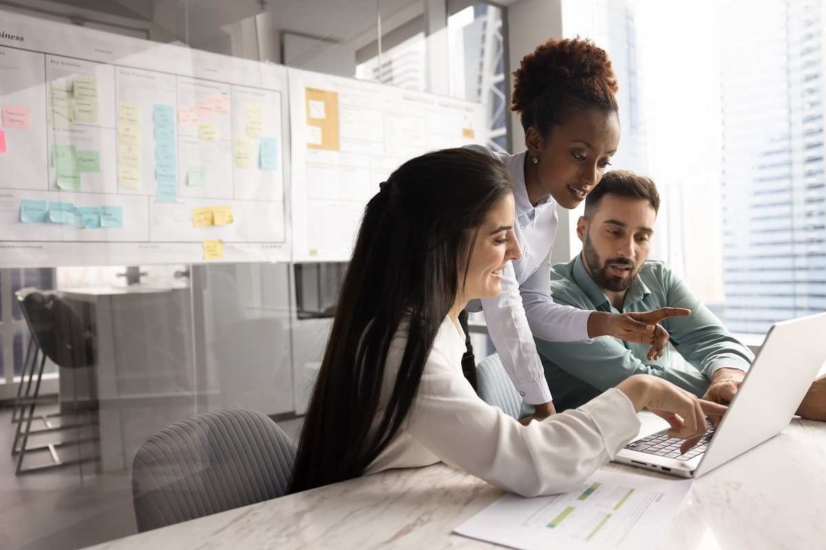 Due diligence team reviewing financial and operational documents on a laptop during a buy-side M&A analysis meeting