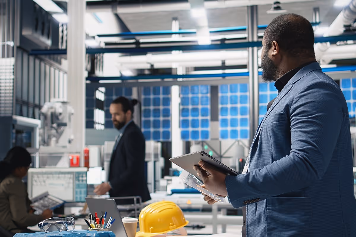 Operations manager conducting a manufacturing site inspection using a tablet to review equipment and production data