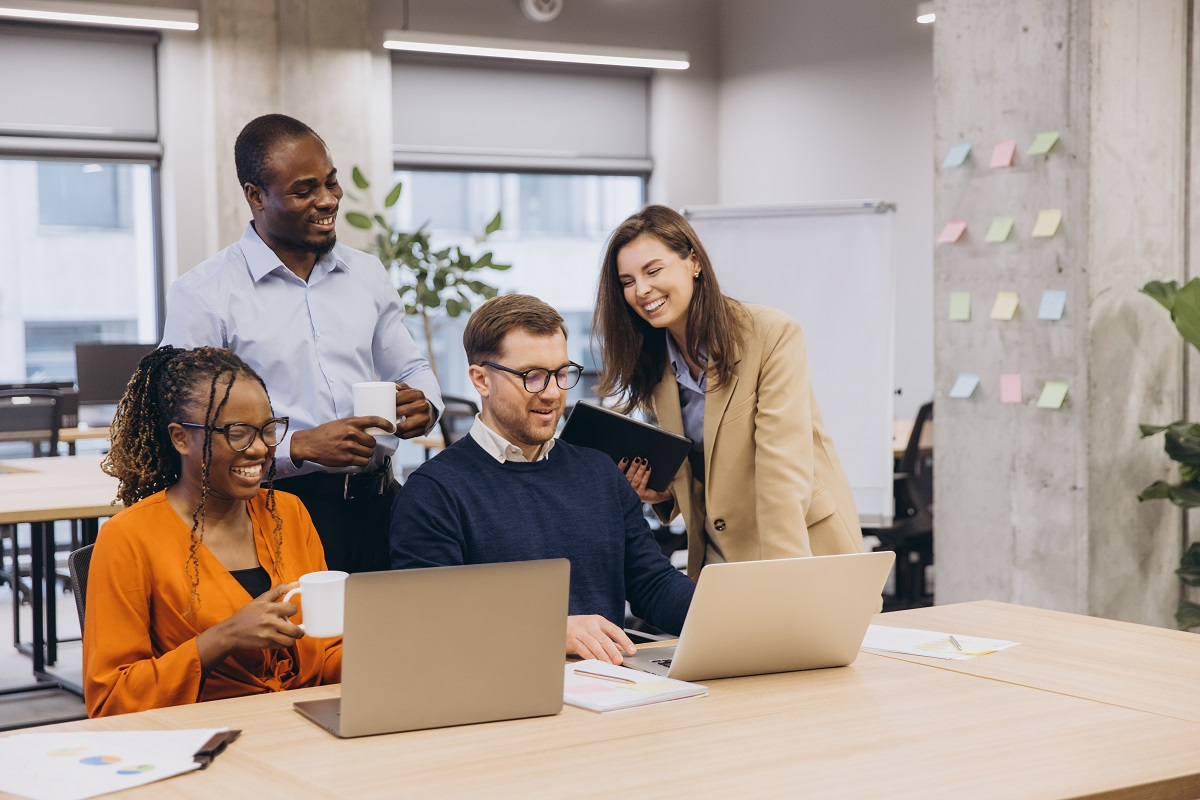 Business team collaborating at laptops reviewing data during due diligence process in modern office