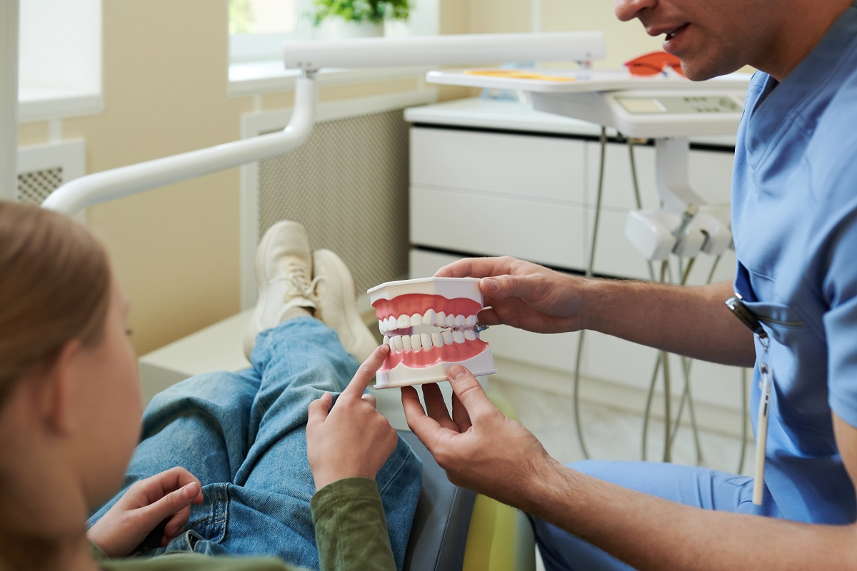 Dentist explaining dental treatment options to a patient using a dental model during a consultation