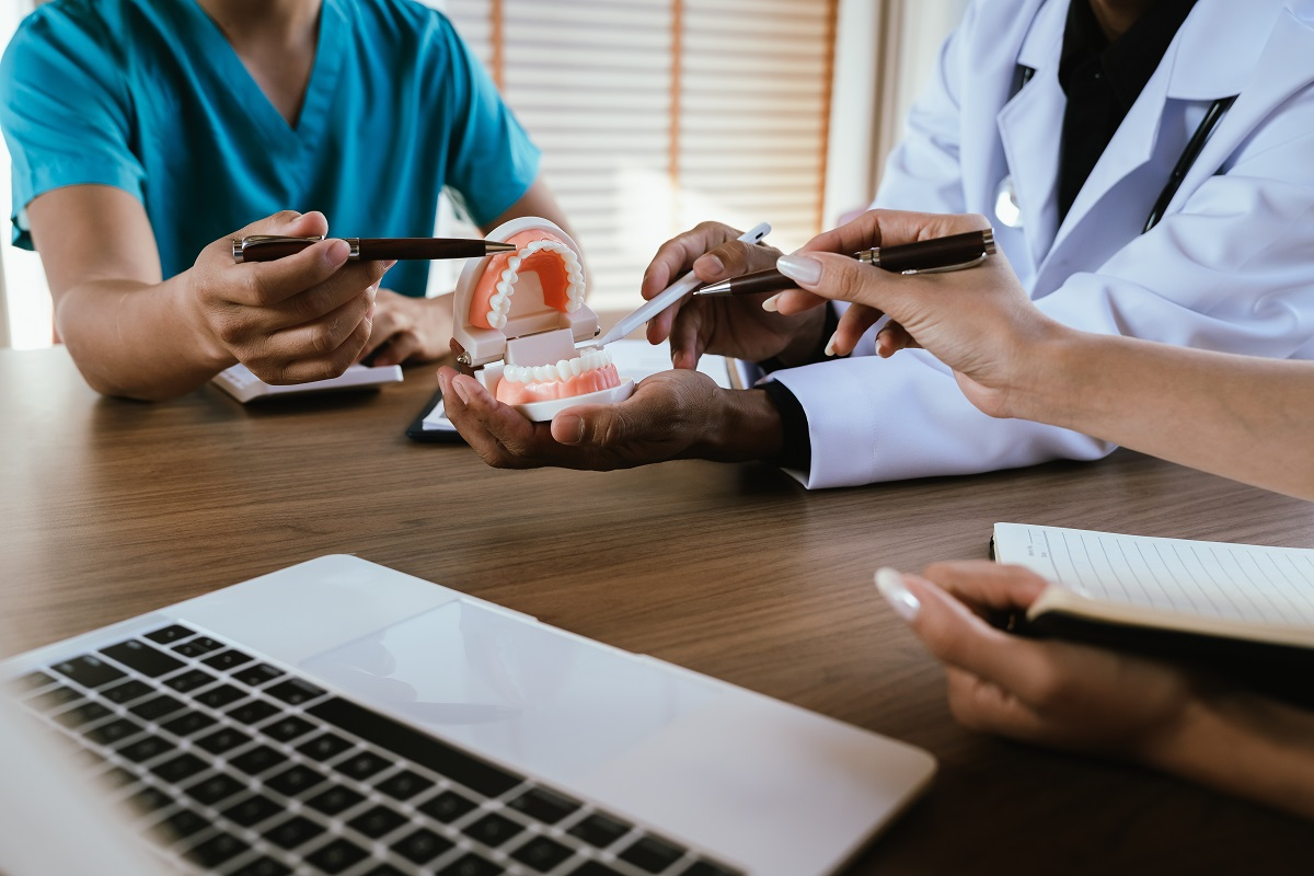 Dental professionals reviewing a dental model and discussing practice operations or treatment planning at a conference table