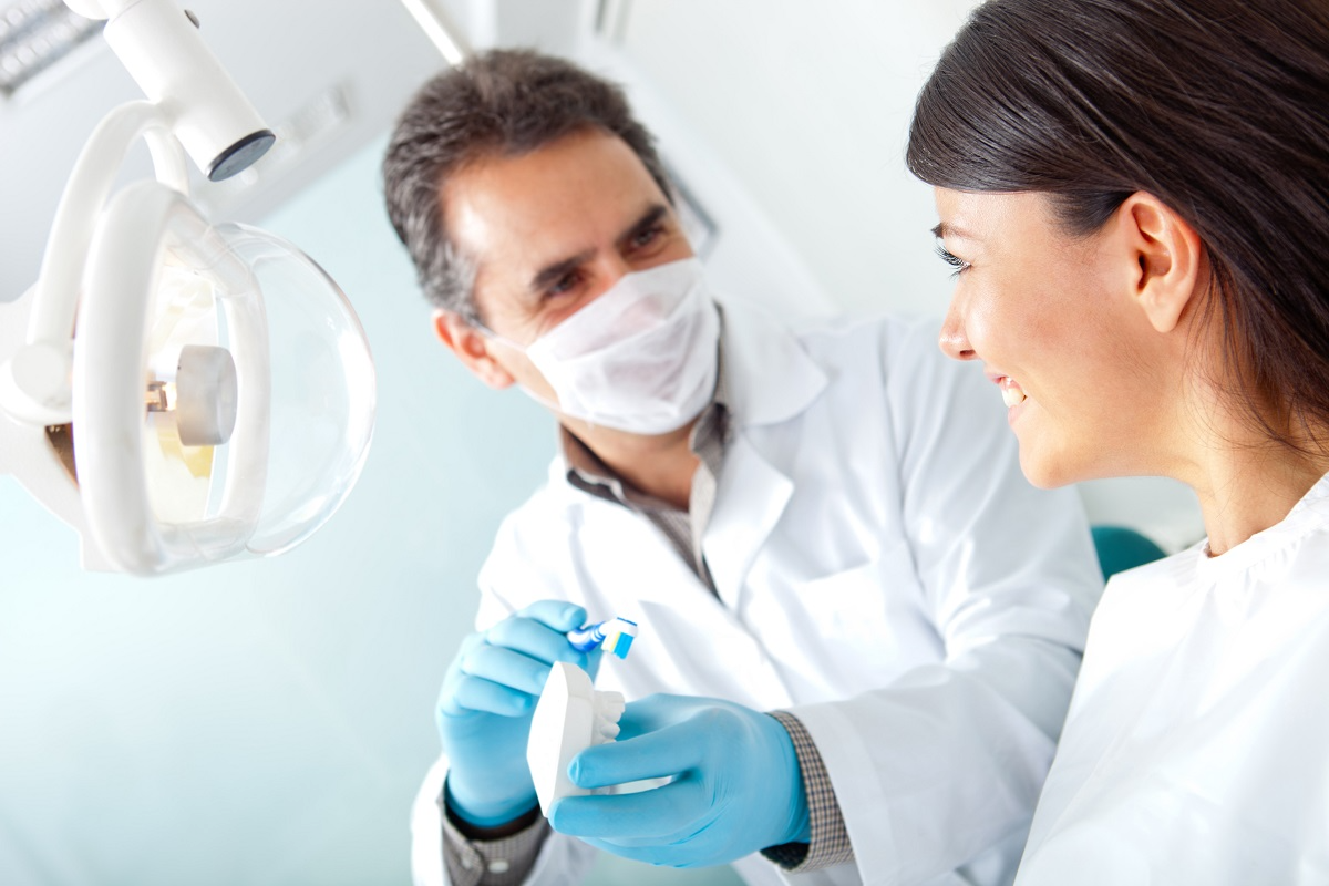 Dentist showing a patient a dental model during a consultation in a modern dental office