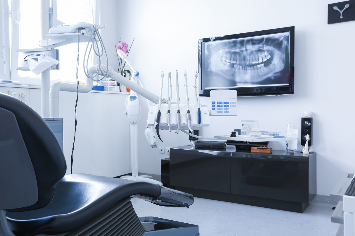 Modern dental practice operatory with dental chair, imaging equipment, and panoramic X-ray display
