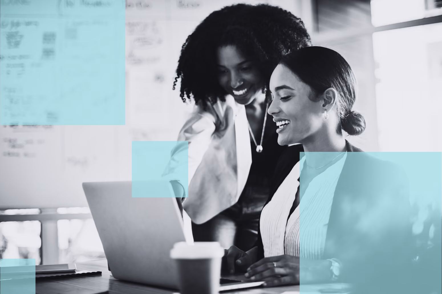 Two corporate development professionals smiling as they work together on a laptop in an office