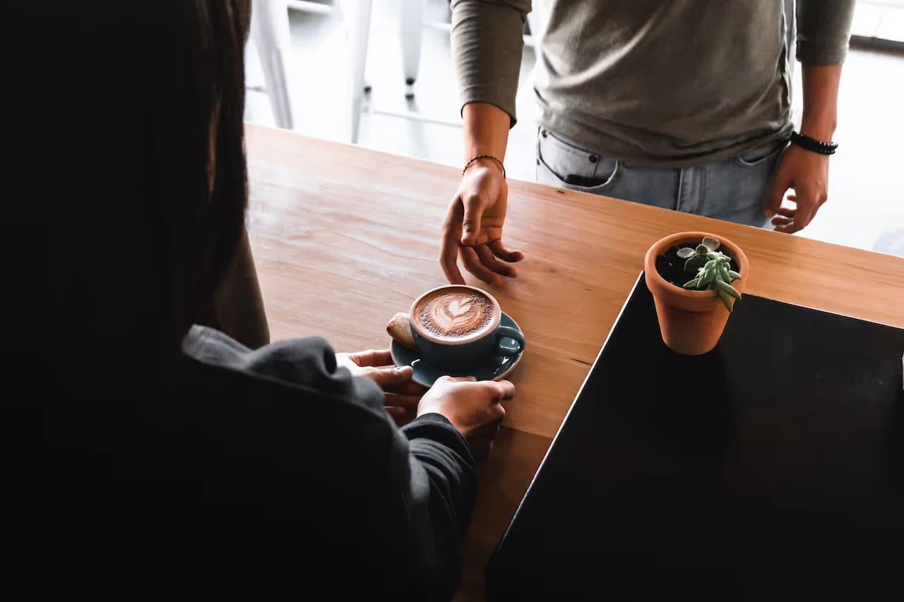 Personne servant un café à un comptoir.