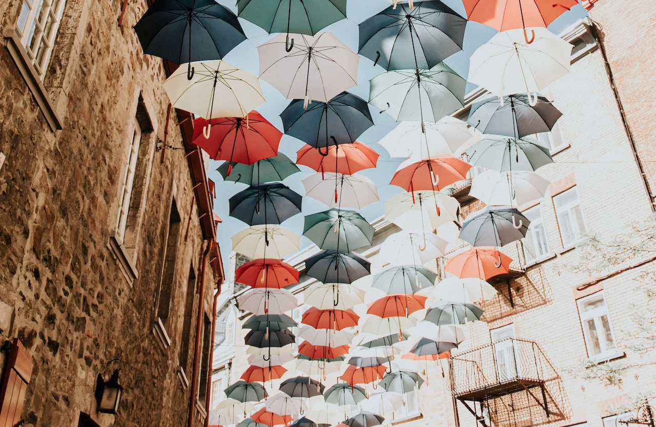 Parapluies colorés suspendus au-dessus d’une rue.