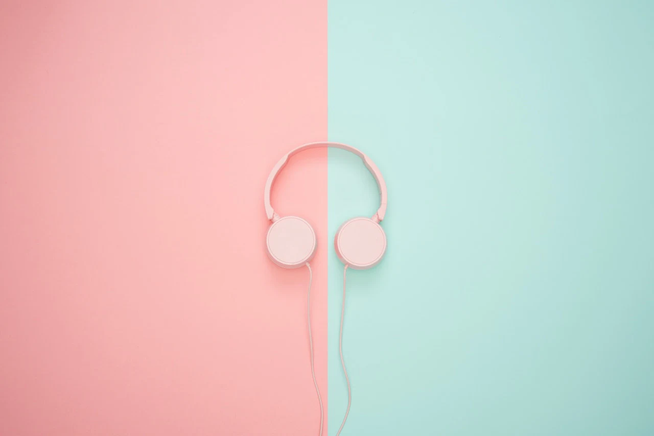 Casque audio rose sur un fond partagé entre rose et bleu.