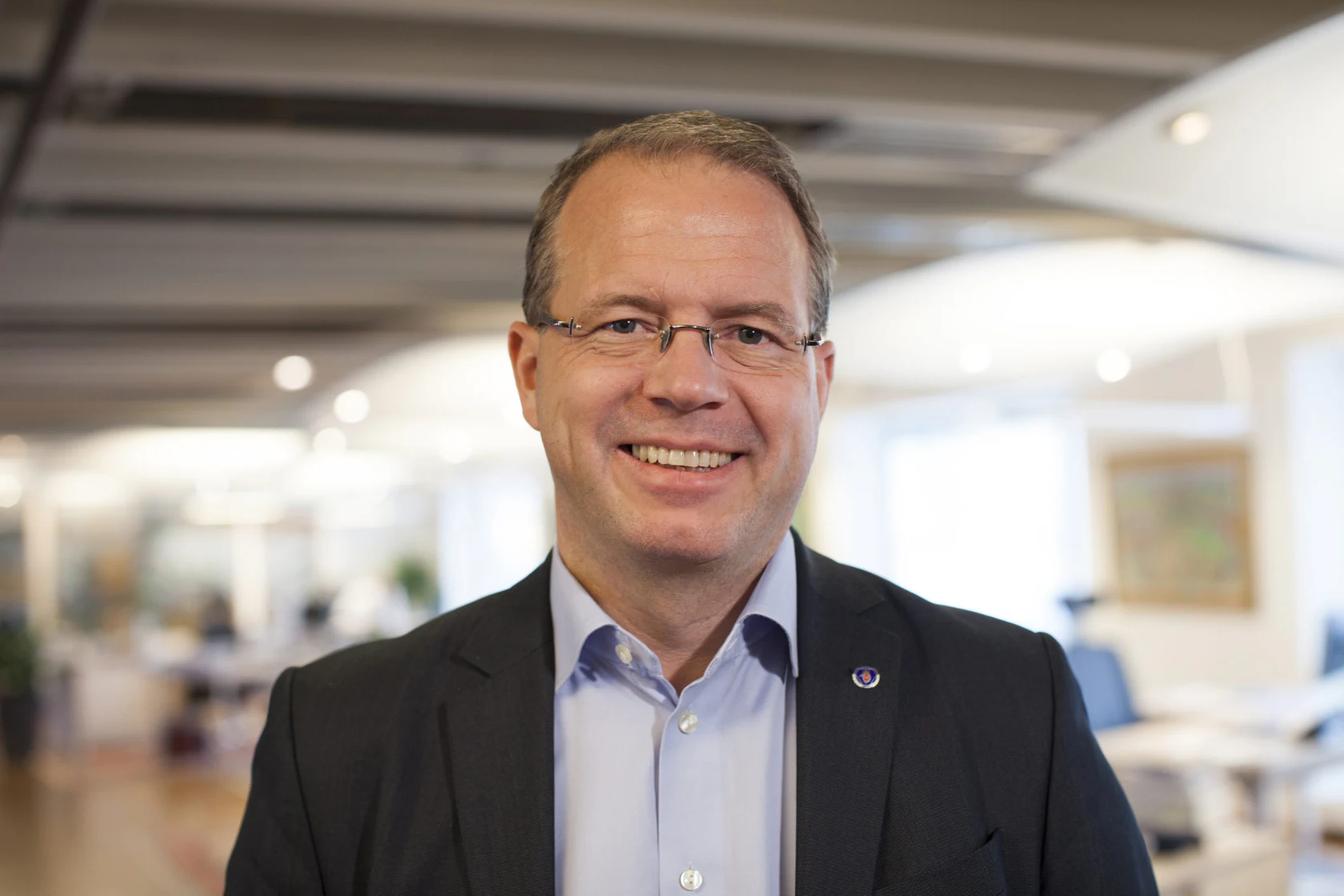 Portrait d’un homme en costume et lunettes dans des bureaux.