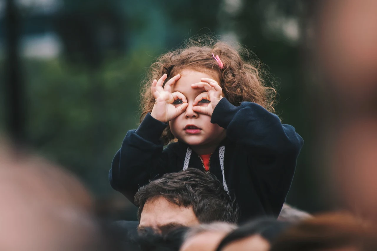 Enfant faisant semblant de regarder à travers des jumelles avec ses mains.