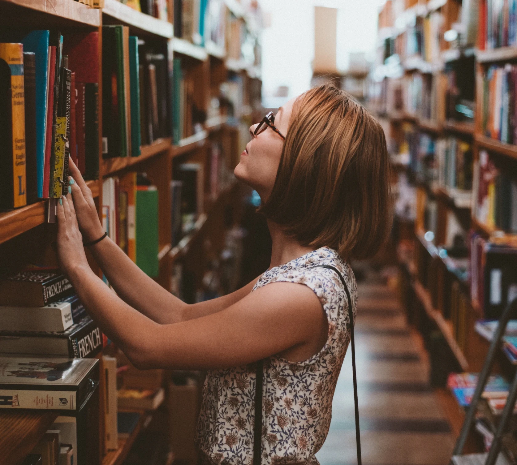 Personne choisissant un livre dans une bibliothèque.