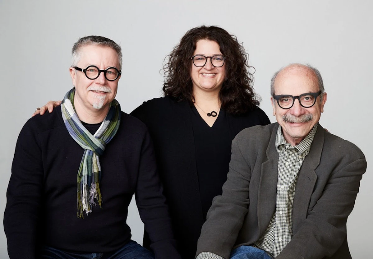 Portrait de trois personnes souriantes posant ensemble.