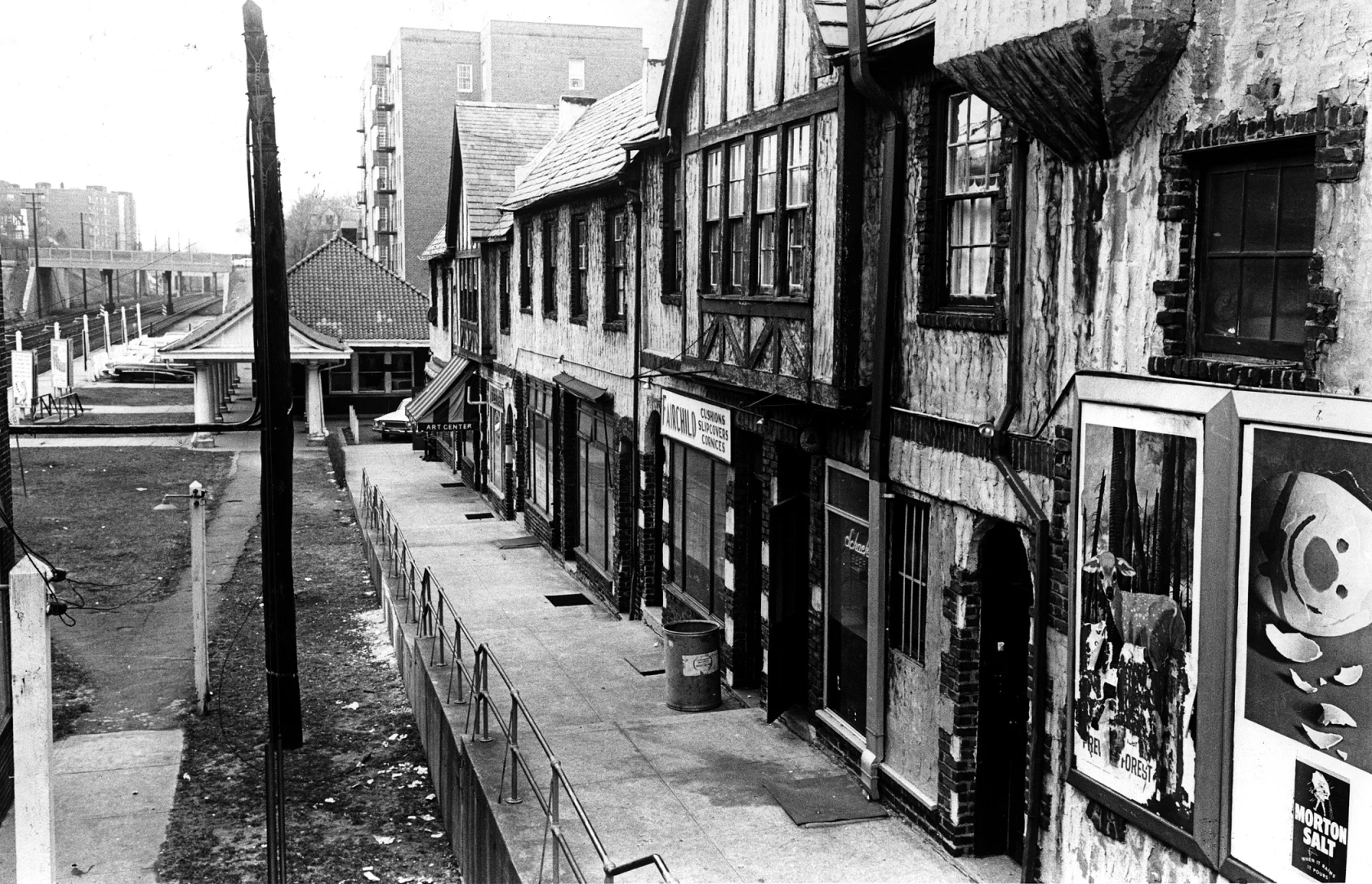 Photographie ancienne d’une rue bordée de commerces et d’habitations.