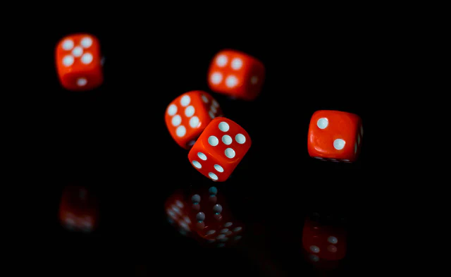 Dés rouges lancés sur un fond noir.