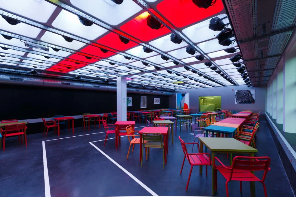 Salle de formation avec tables et chaises rouges.