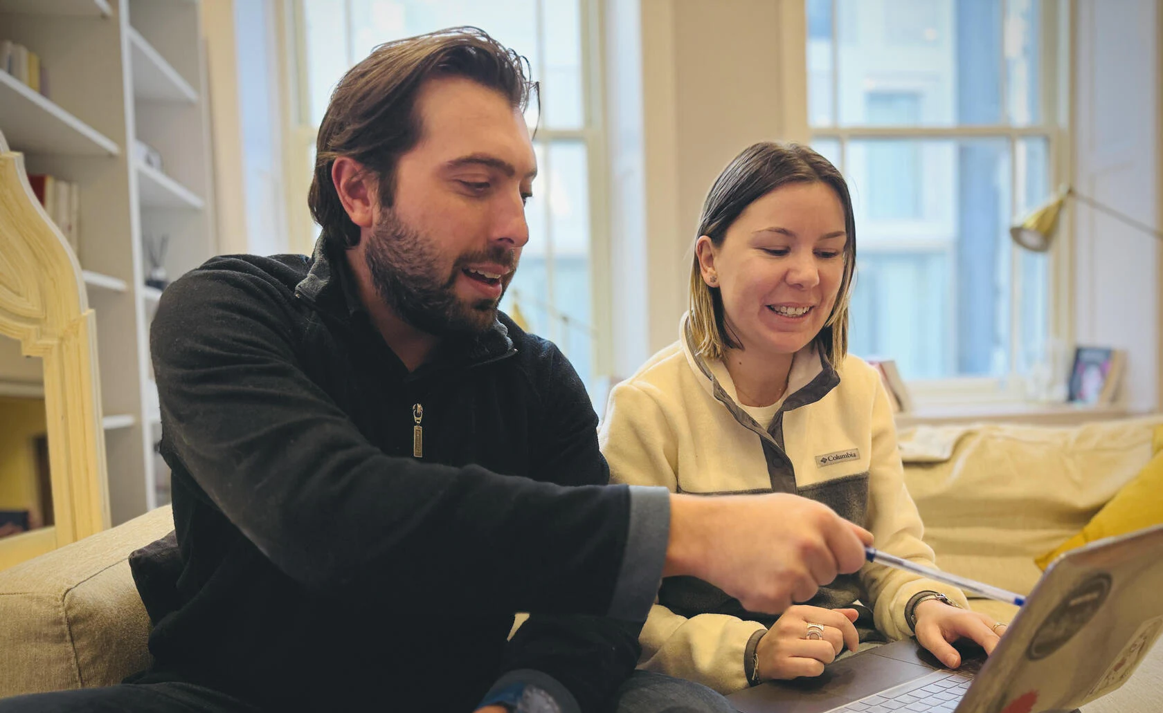 Deux collègues échangent devant un ordinateur portable.