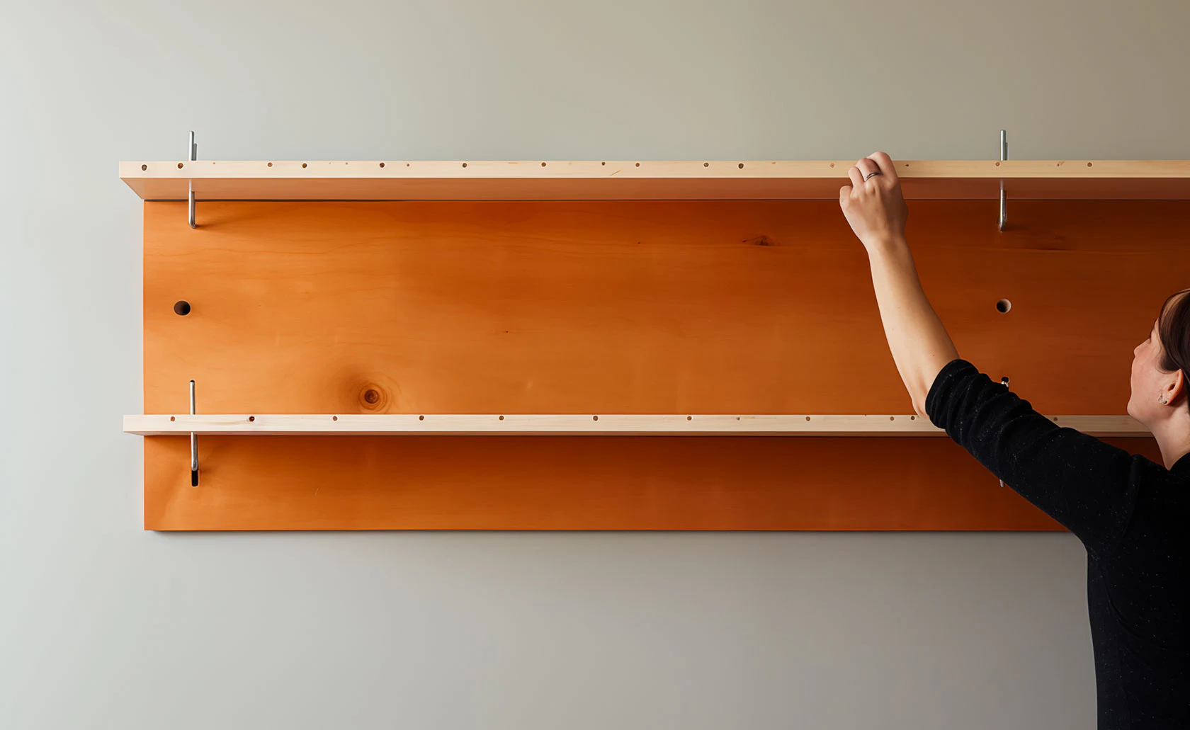 Personne assemblant un meuble en bois fixé au mur.