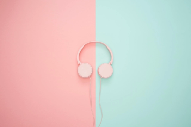 Casque audio rose sur un fond partagé entre rose et bleu.