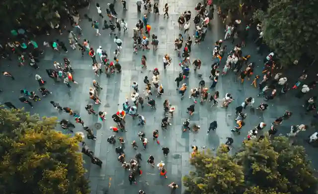 Foule vue du dessus sur une place entourée d’arbres.