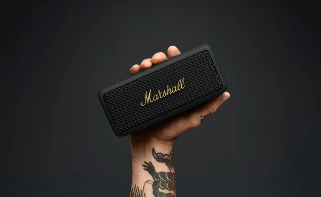 Main tatouée tenant une enceinte portable Marshall.