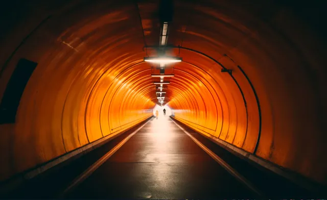 Long tunnel orange avec une sortie lumineuse.