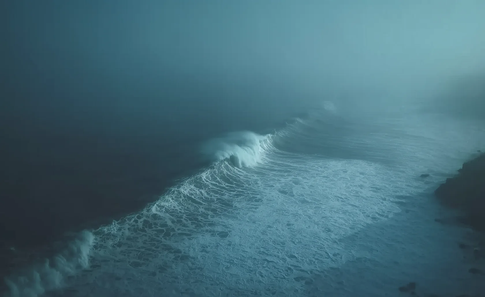 Vagues déferlant sur une côte dans la brume.