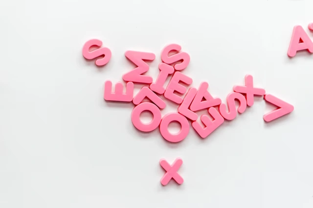 Lettres roses éparpillées sur un fond clair.