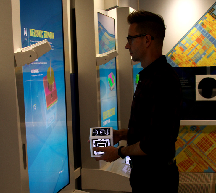 Intel Museum exhibit person standing in front of large screen holding lighted cube to control exhibit