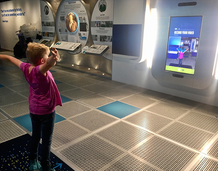 Child with arms up demonstrating Intel Augmented Reality Photo Booth