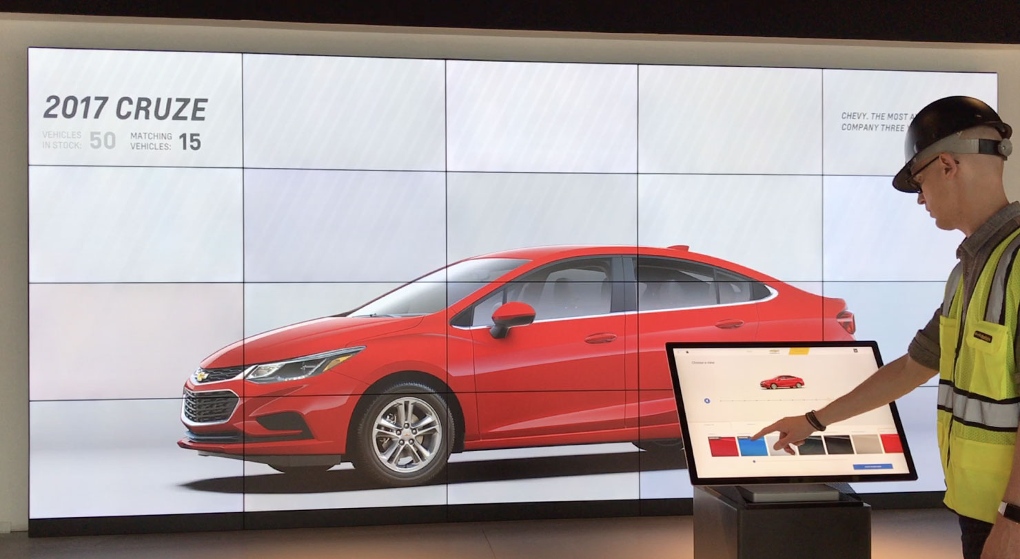 Large video wall with life-size Chevy car and person interacting with podium screen to control large screen