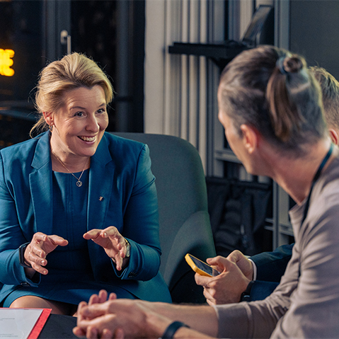 A diverse group of people seated indoors, engaged in conversation while waiting for an event to start.