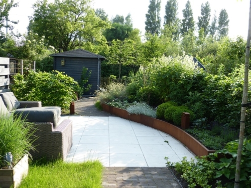 De ronde vorm van de verhoogde border leidt de blik verder de tuin in.