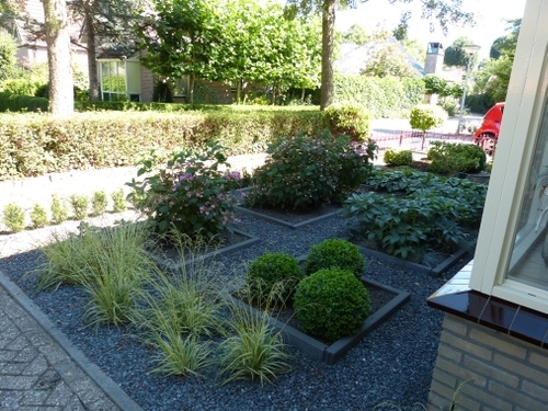 Onderhoudsarme voortuin met split, plantvakken, bloeispreiding, siergrassen en groenblijvende vaste planten.