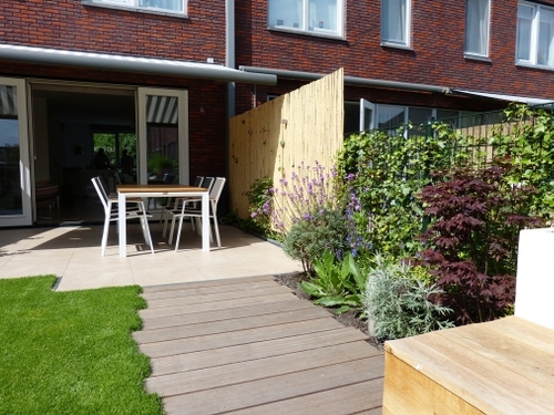 De hardhouten planken van het vlonder pad liggen versprongen ten opzichte van elkaar voor een speels beeld.