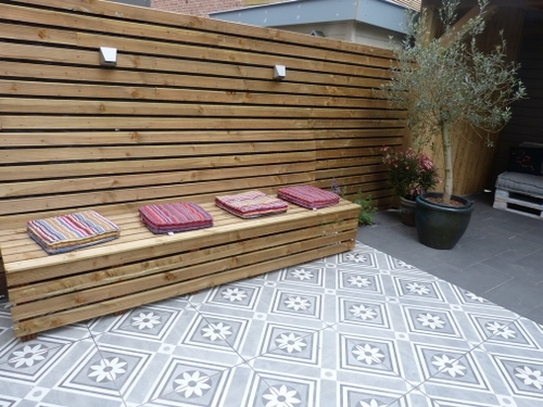 De diepe eettafel bank in deze tuin is geïntegreerd met de schutting.