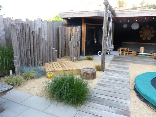 Van verticale ronde palen is een muurtje gemaakt voor de buitendouche.