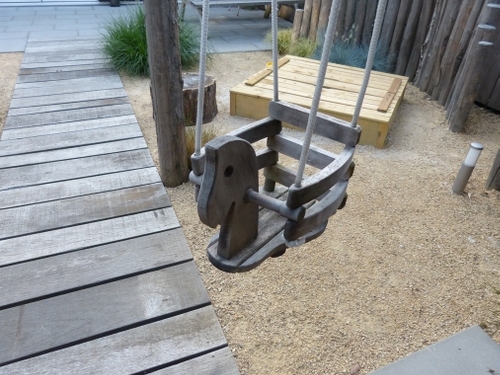 Een schommel en een zandbak in deze strandtuin.