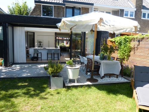 Zicht op het terras bij de keuken met glazen schuifwand vanuit de overkapping.